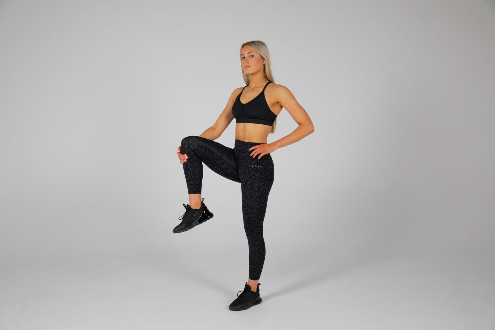 Maria Savage mid warm-up in the studio, knee raised, leopard-print leggings.