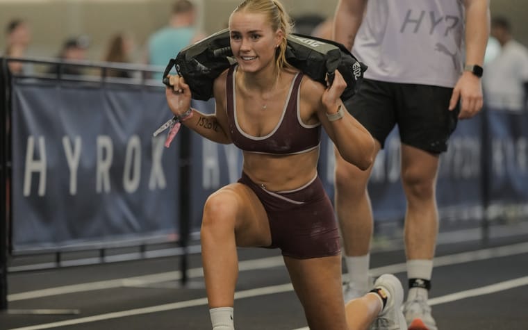 Maria carrying a sandbag during her first Hyrox event.