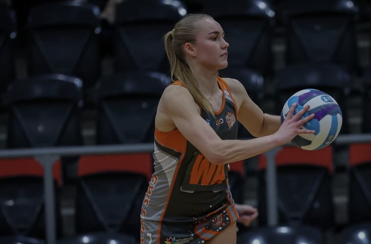 Maria playing netball, catching the ball mid-match.