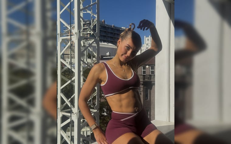 Maria on a rooftop, arm raised, city skyline behind her.